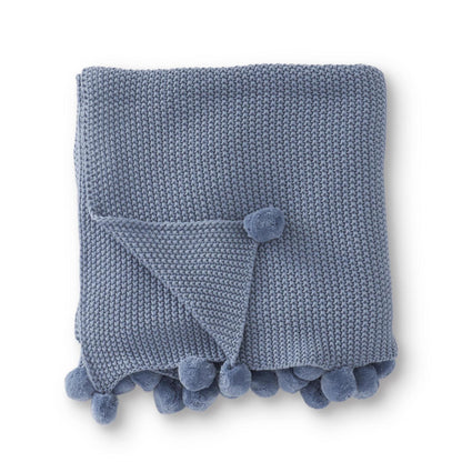 Colcha tejida celeste con borde de pompones
