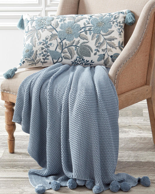 Colcha tejida celeste con borde de pompones
